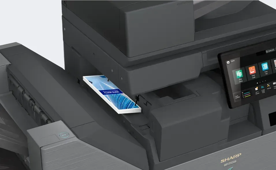 Smartphone resting on a Sharp multifunction printer; black and gray, screen showing interface.