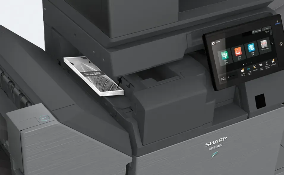 Smartphone resting on a Sharp multifunction printer; black and gray, screen showing interface.