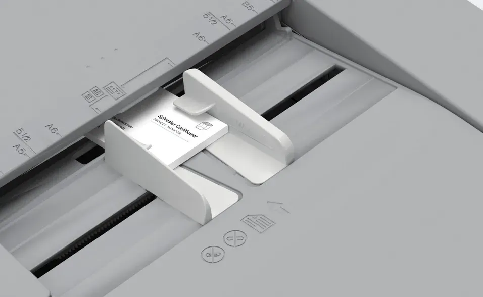 Close-up of a scanner bed with a white guide holding a business card in place for scanning.