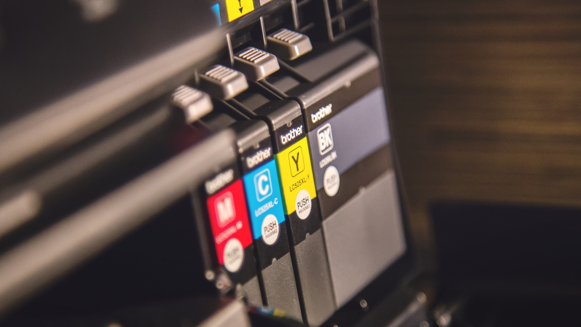Close-up of printer ink cartridges labeled Magenta, Cyan, Yellow, and Black, installed in a printer.