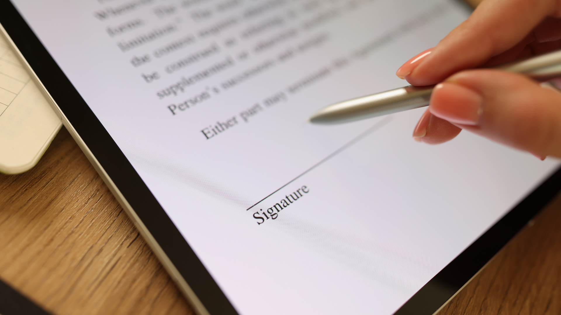 A person signing a document on a tablet with a stylus. Close up shot of hand and screen.