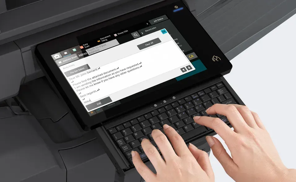 Person typing on a keyboard attached to a printer's touchscreen, displaying a document.