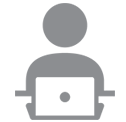 Person sitting at a laptop, working. Gray icon.