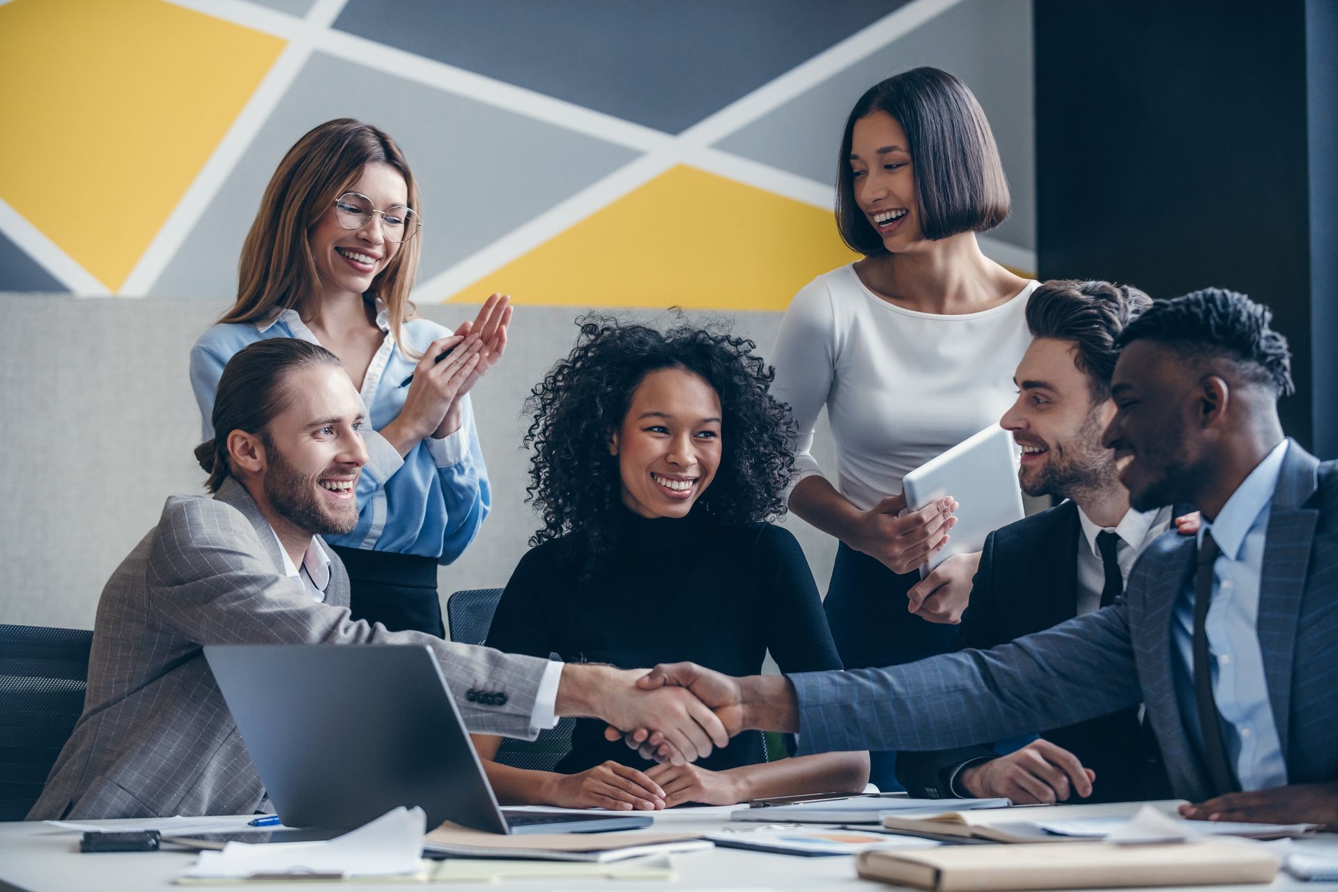 Equipe de profissionais de TI em uma reunião, celebrando um acordo e discutindo estratégias de alocação