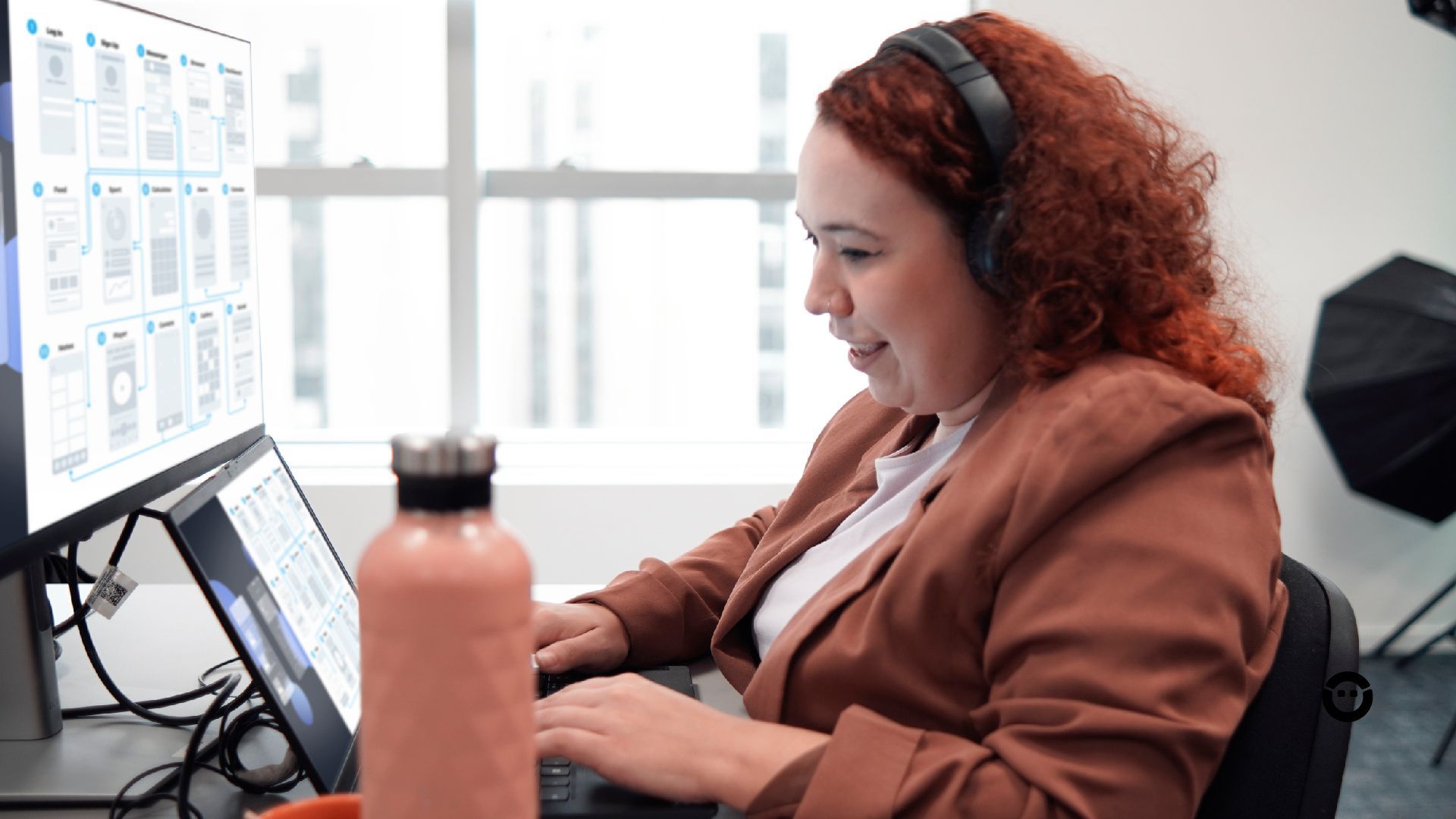 Uma mulher usando fones de ouvido enquanto usa um trabalha na experiência do usuário de um site.