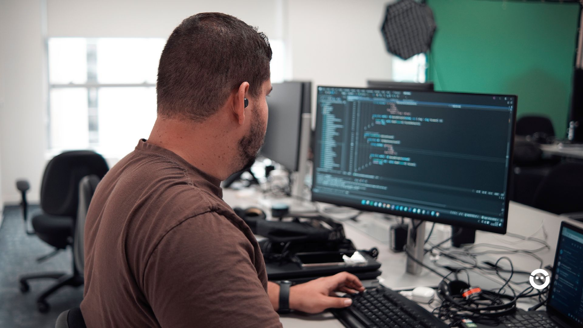 Um homem trabalhando em frente a um monitor de computador, ajustando melhorias de UX design.