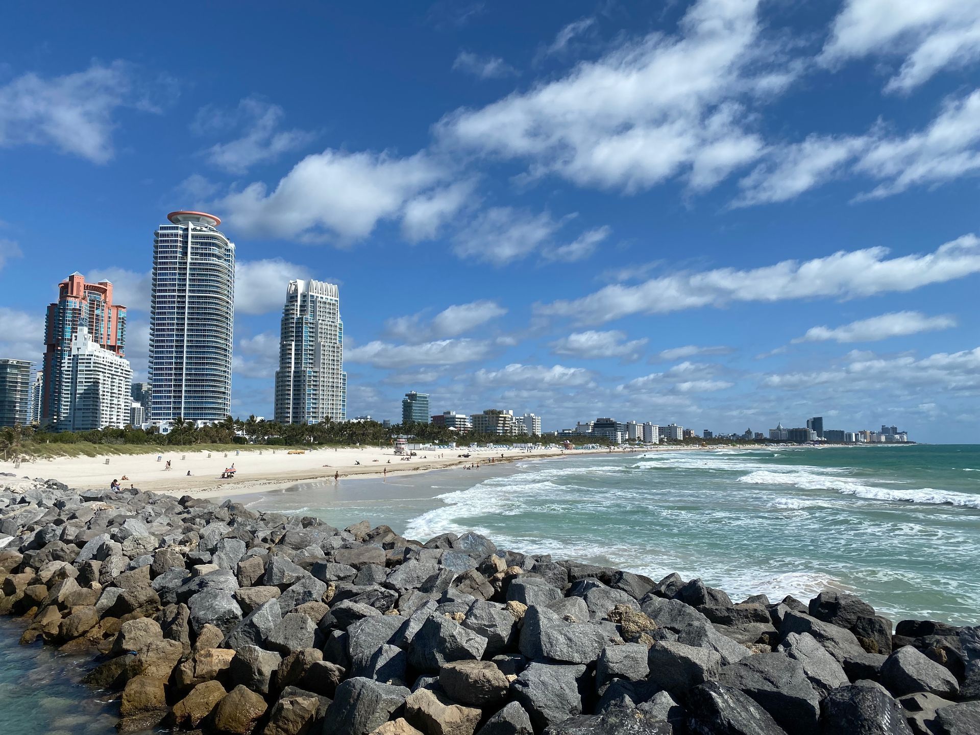 A beach with a lot of rocks and buildings in the background