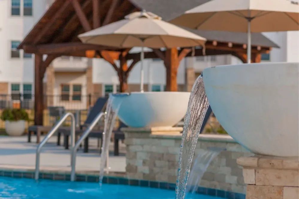 Pool with cascading fountains, gazebo, and umbrellas.