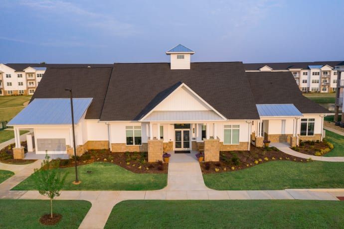 White building with dark roof, blue accents, and a landscaped lawn.