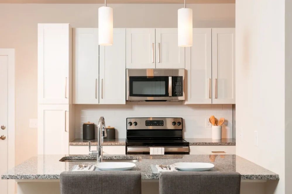 Modern kitchen with white cabinets, stainless steel appliances, and a granite countertop island.