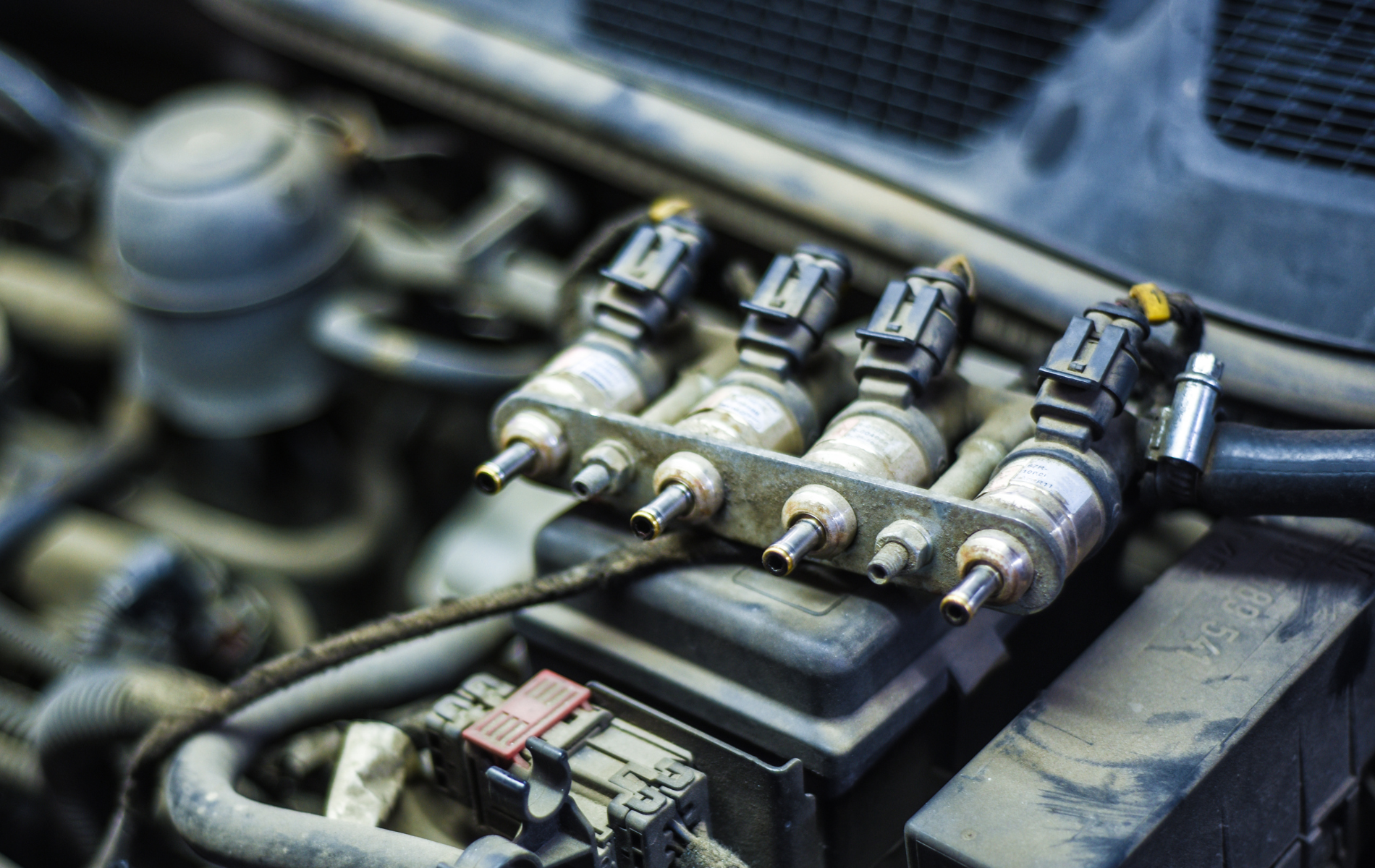 Close-up of a car engine's fuel injectors, showing a cluster of four nozzles and electrical connectors.