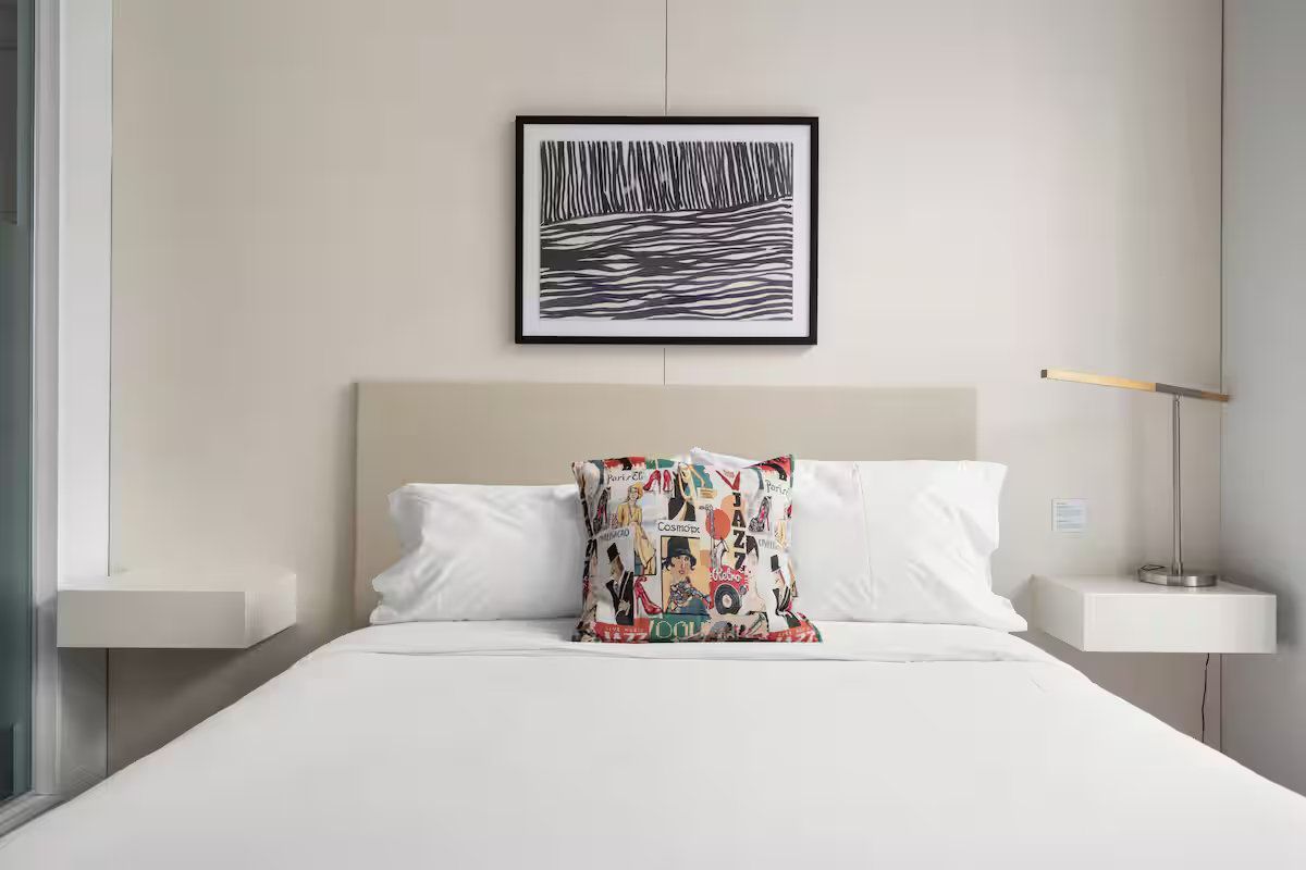 Bedroom with bed, floating nightstands, and abstract art.