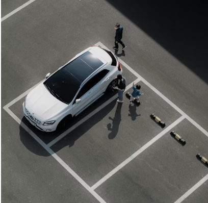 Dark purple car parked in a garage, with a white car in the background.