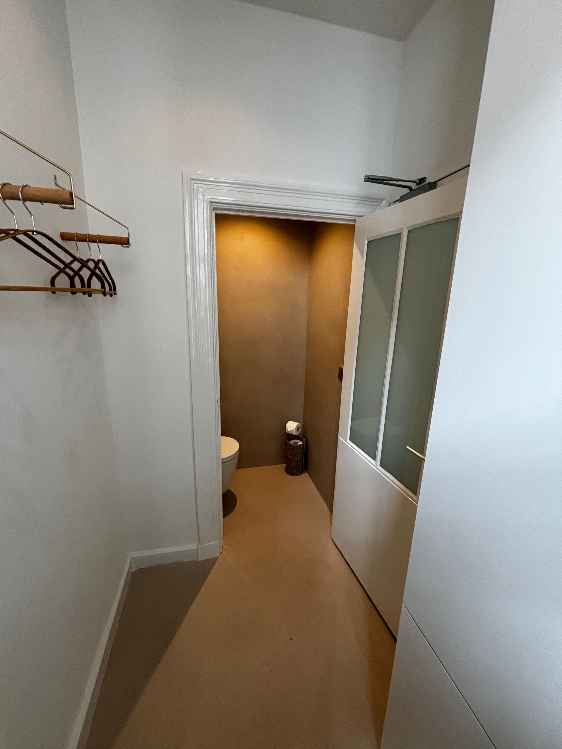 Een gang met daarin een toilet en een prullenbak