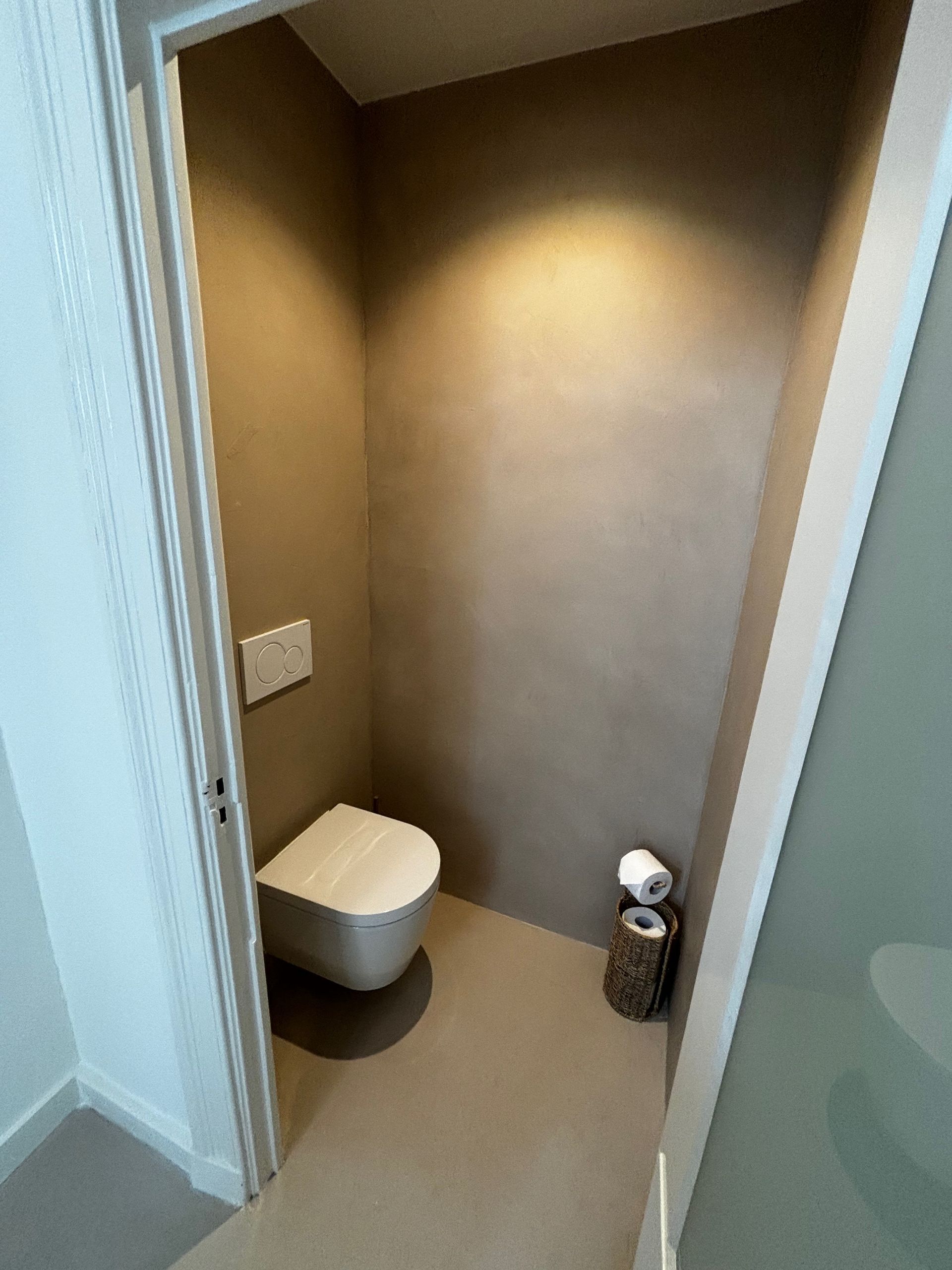 Een badkamer met toilet en een rol wc-papier.