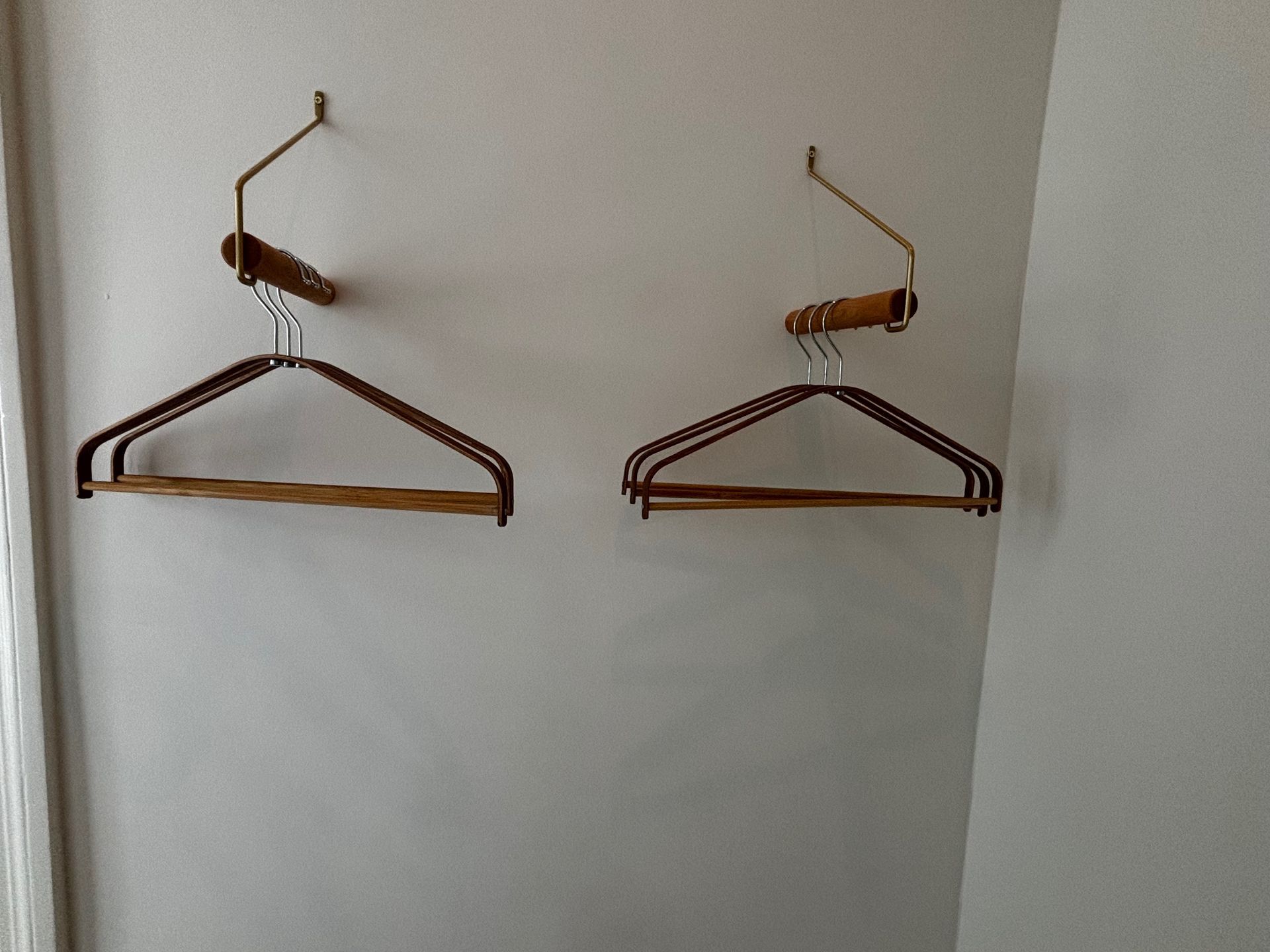 Aan een witte muur hangen twee kleerhangers
