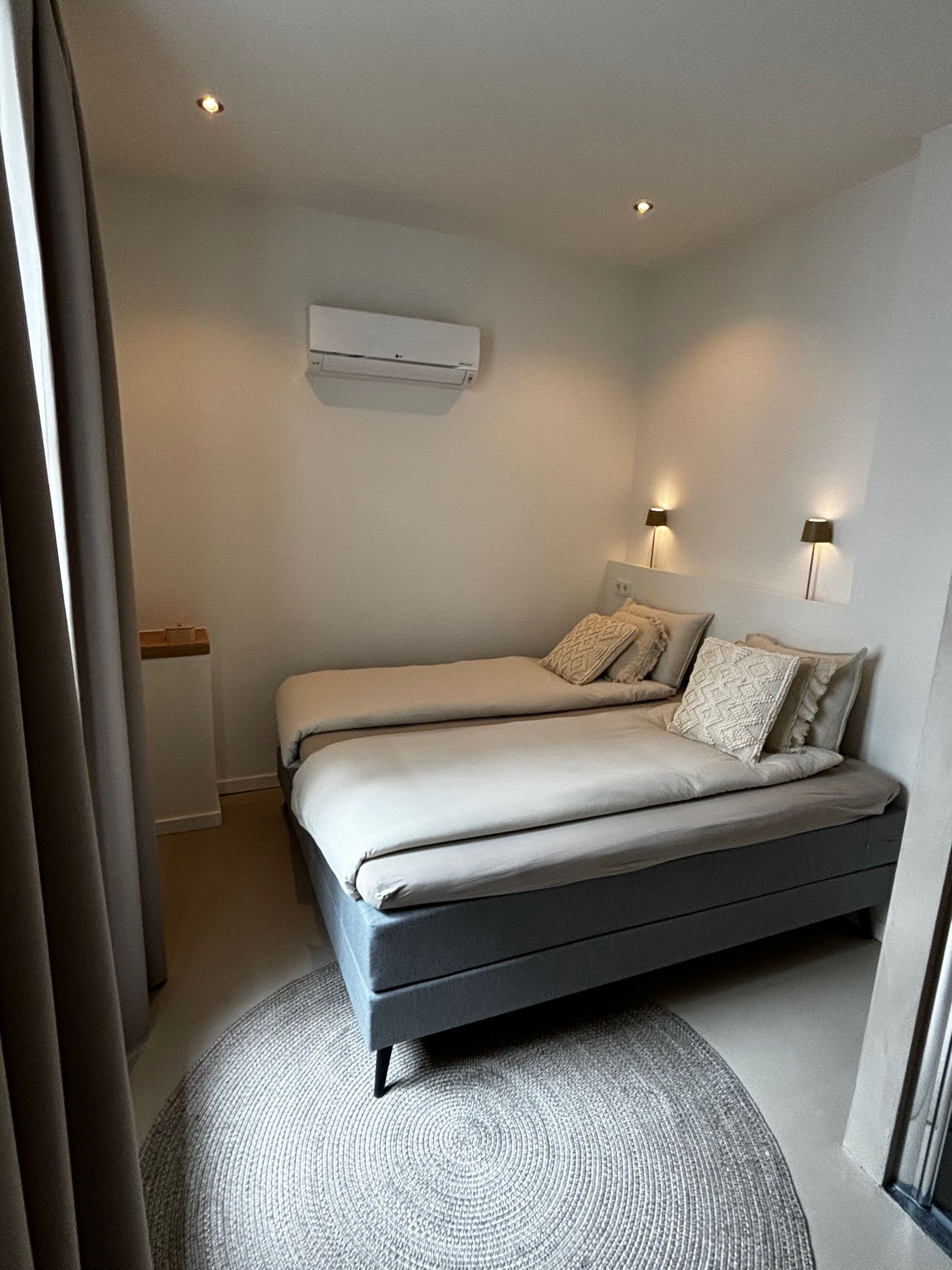 Een slaapkamer met twee bedden, een vloerkleed en een raam.