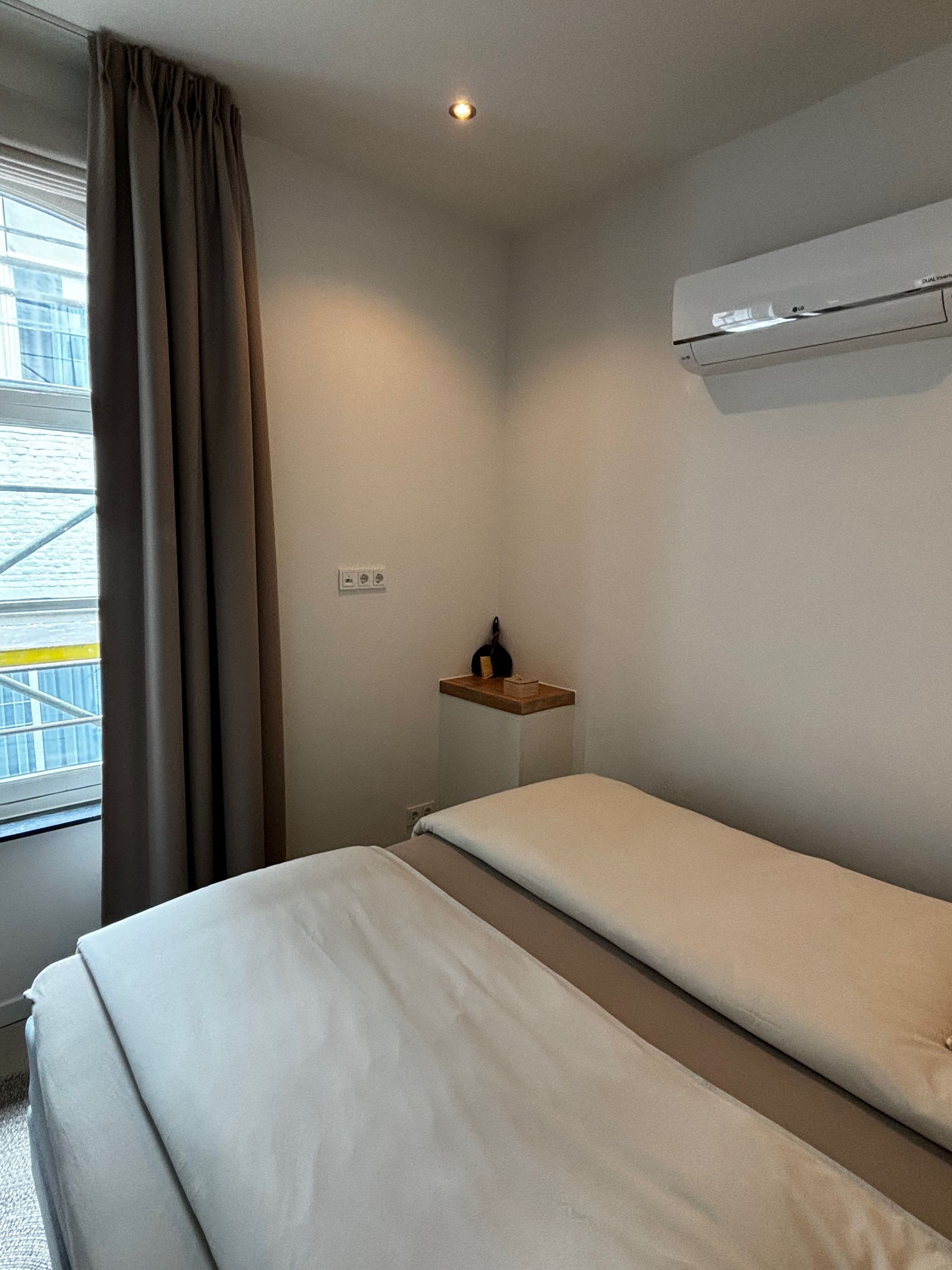 Een slaapkamer met een bed, raam en airconditioning.