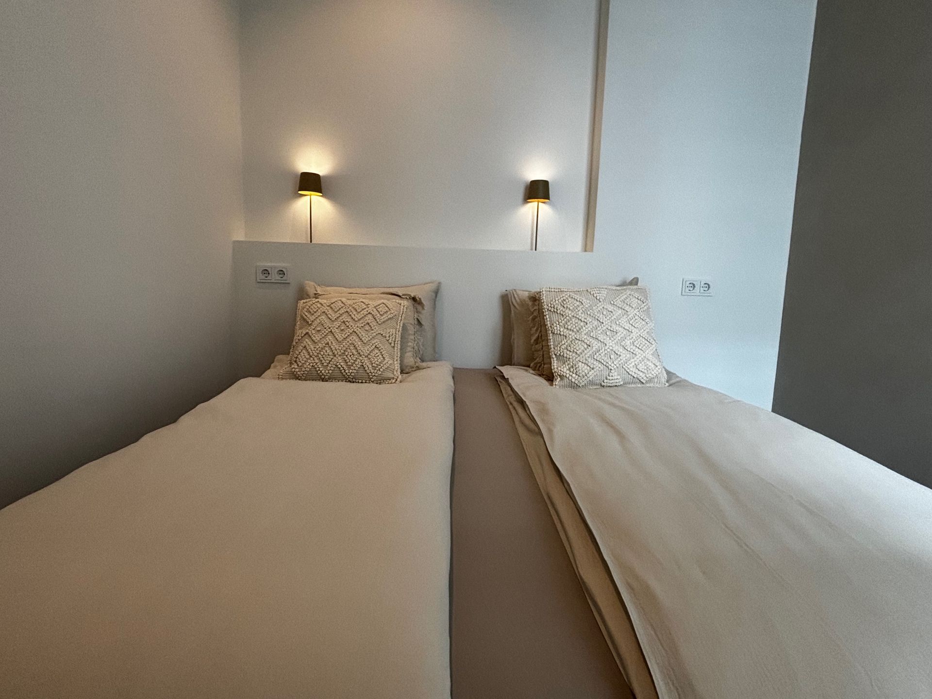 Een slaapkamer met twee bedden en twee lampen aan de muur