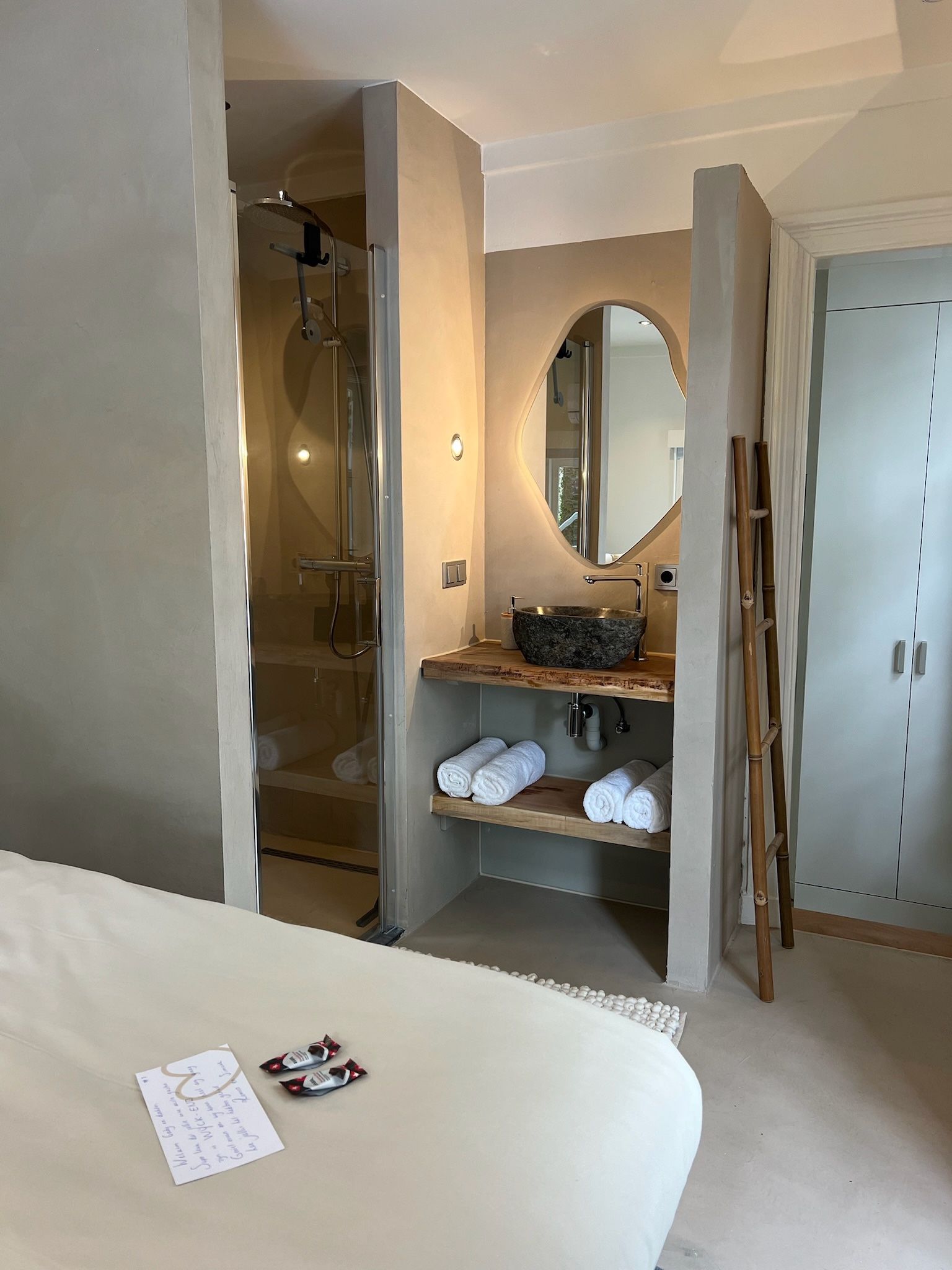 Een slaapkamer met wastafel, spiegel en douche.