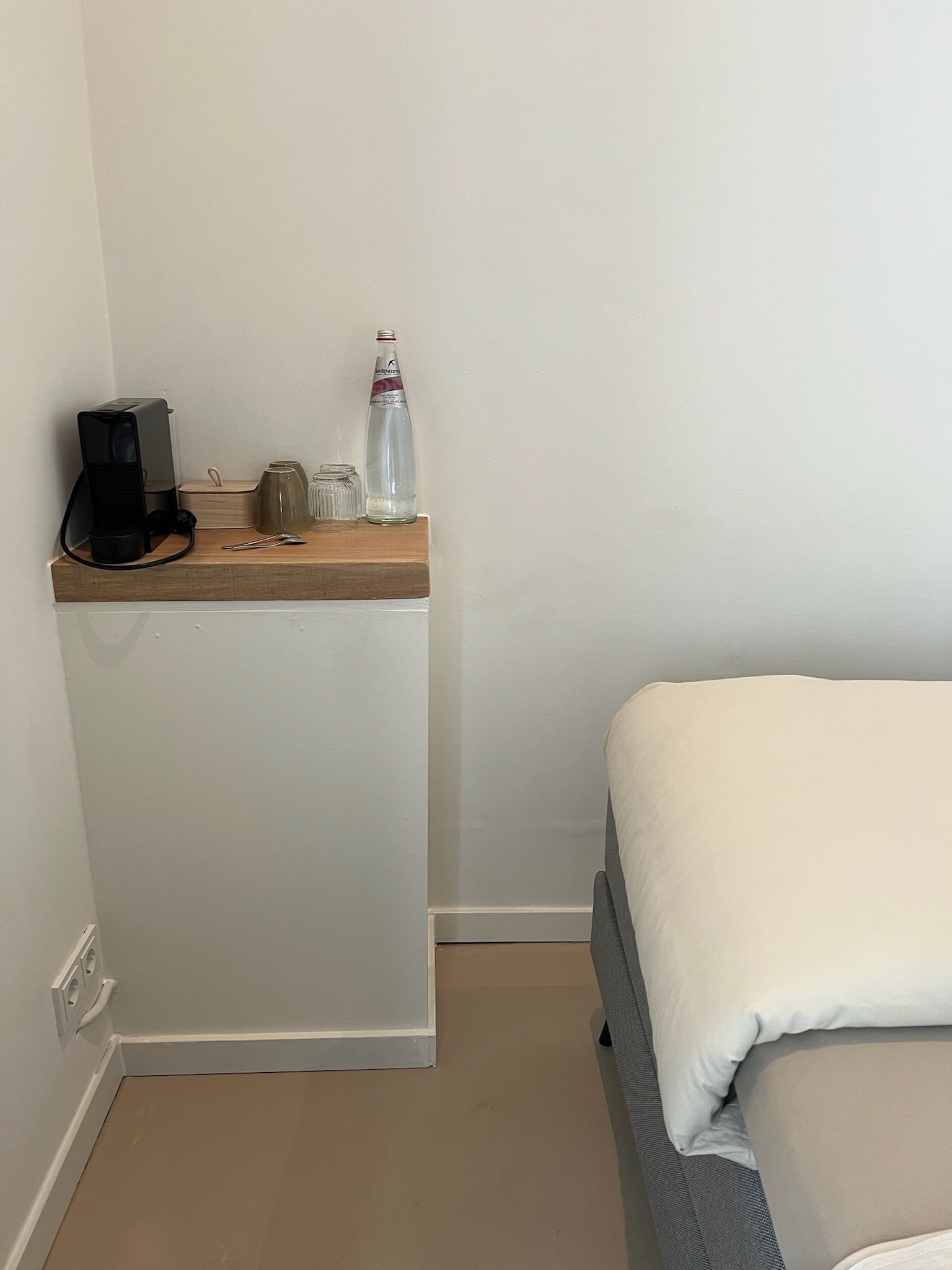 Een slaapkamer met een bed en een tafeltje met een koffiezetapparaat erop.