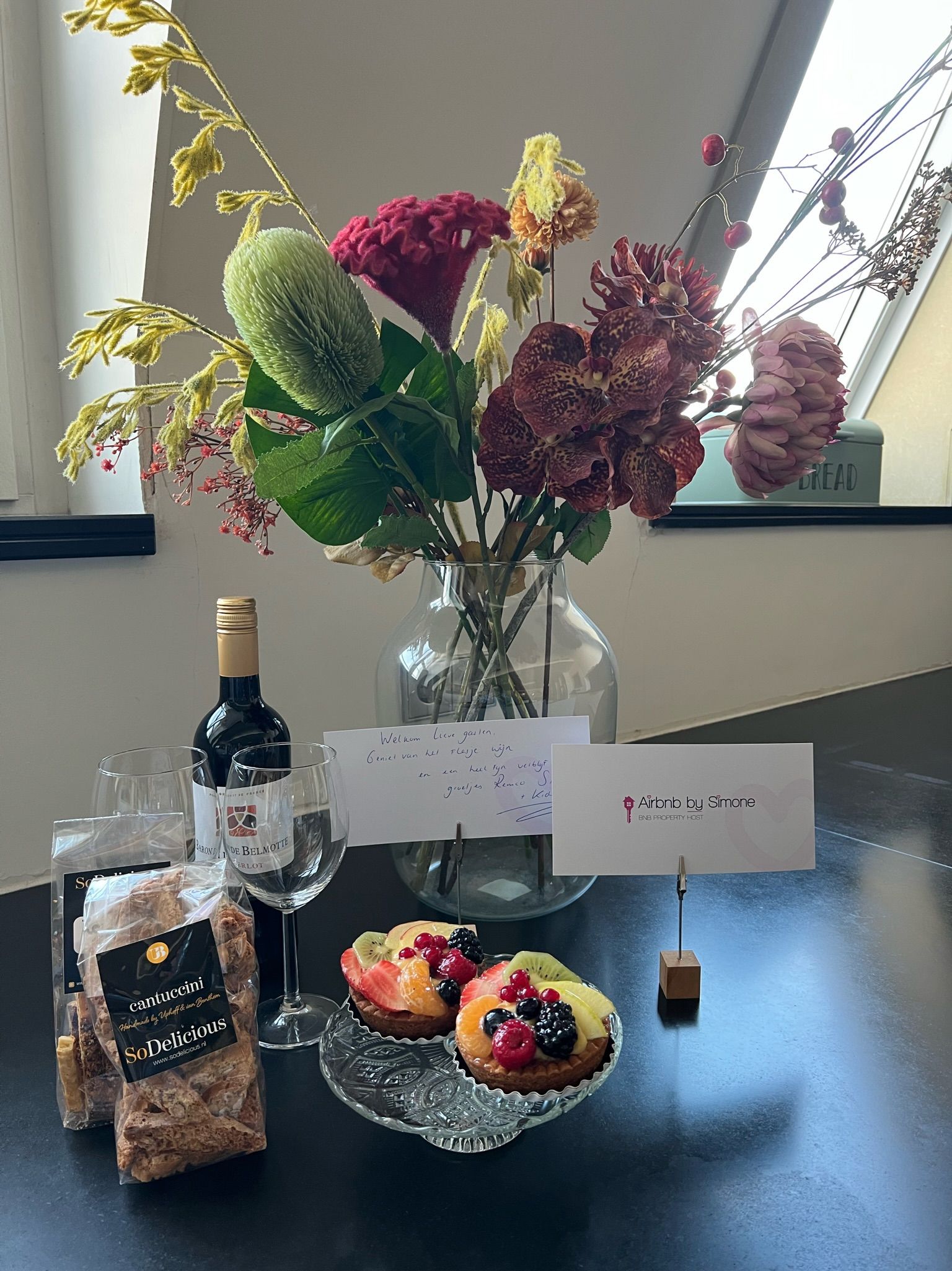 Een tafel met een vaas met bloemen en een fles wijn