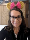 A woman wearing glasses and minnie mouse ears is smiling for the camera.