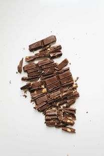 A pile of chopped chocolate bars on a white surface.