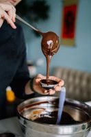 Cormier Confection's, Dawn is pouring chocolate into a bowl with a spoon.