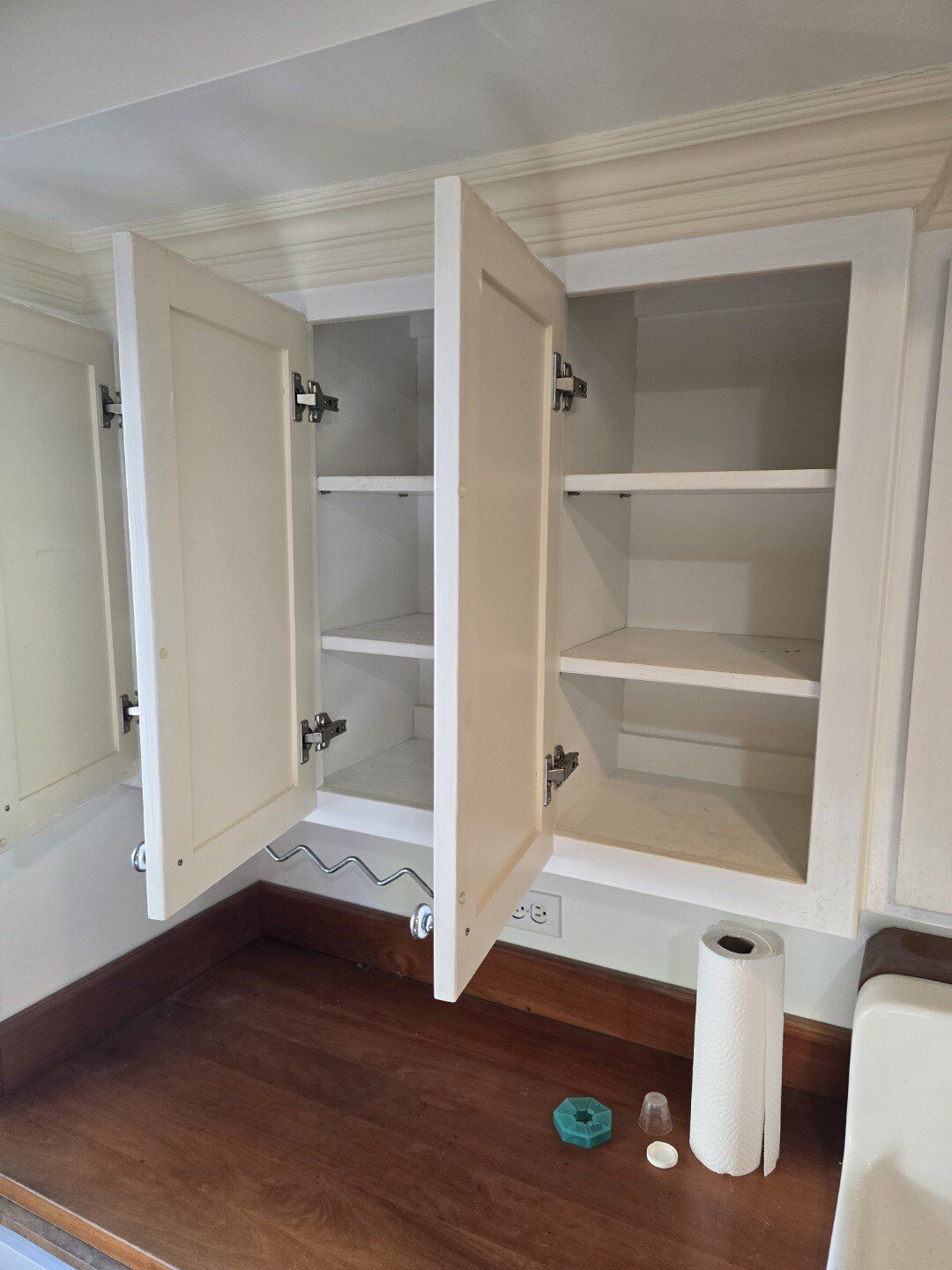 A kitchen cabinet with the doors open and a roll of paper towels on the counter.