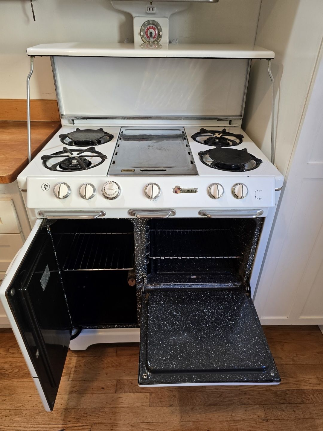 A white stove with the door open in a kitchen.