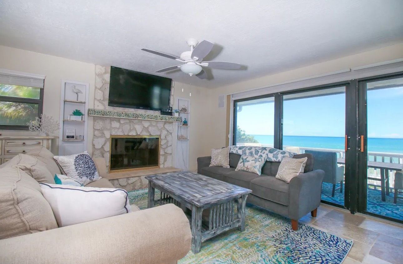 A living room with a couch , coffee table , fireplace and television.