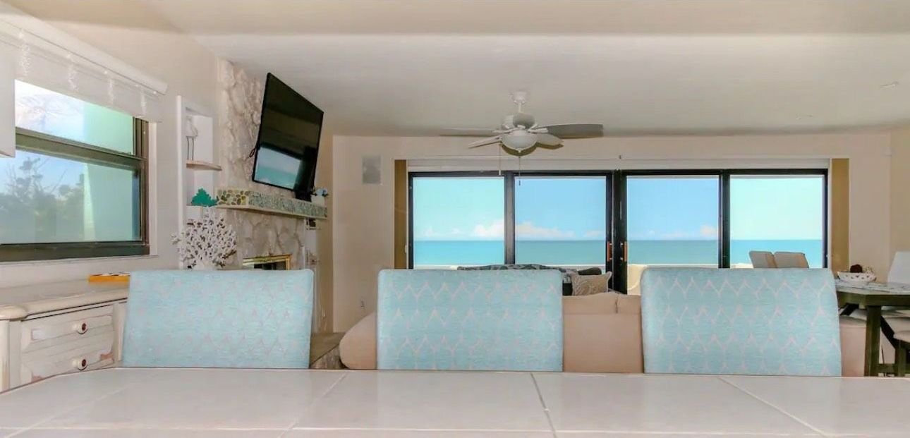 A living room with a table and chairs and a view of the ocean.