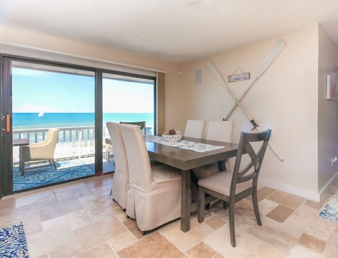 A dining room with a table and chairs and a view of the ocean.
