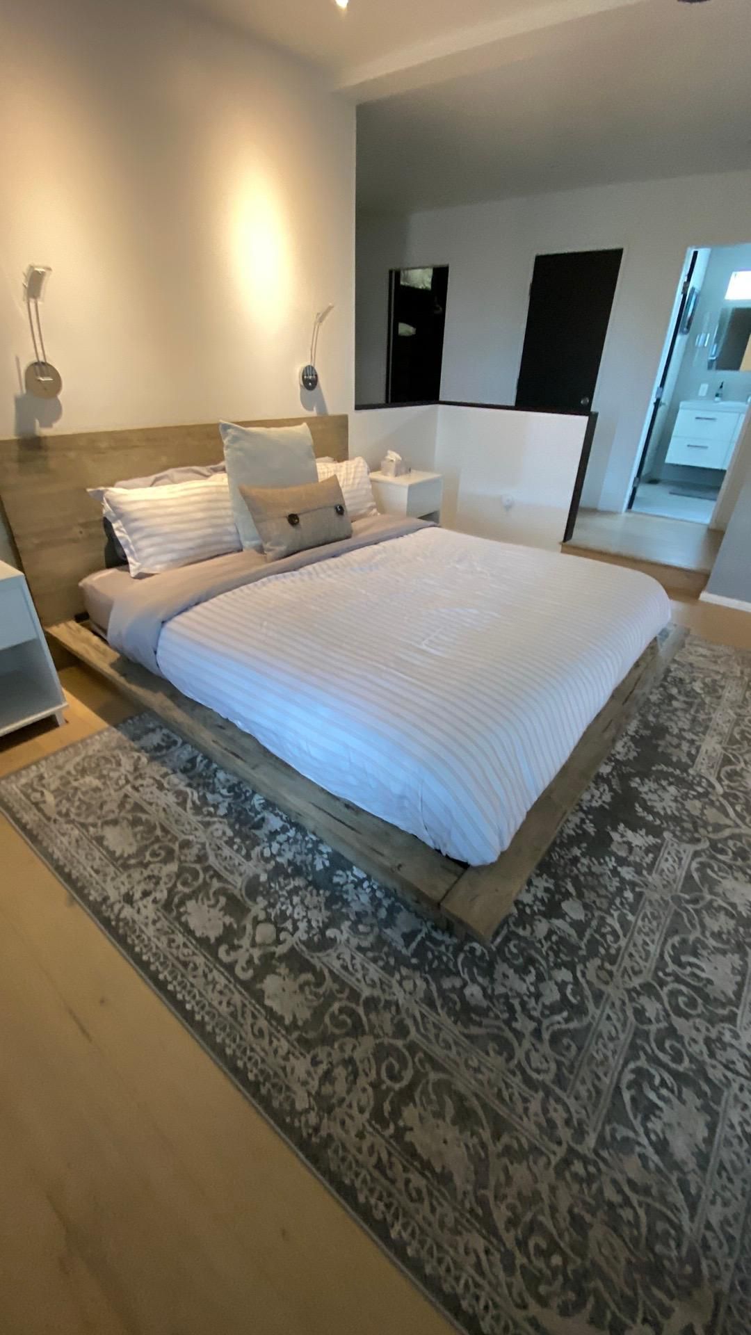 A bedroom with a large bed and a rug.