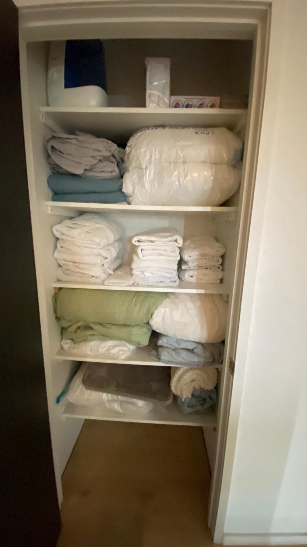 A closet filled with lots of clothes and pillows.