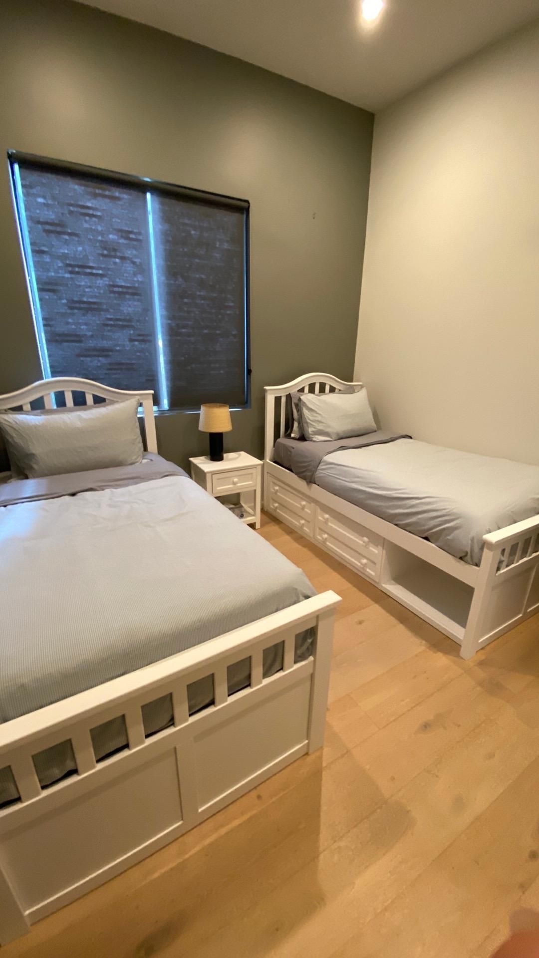 A bedroom with two twin beds and a window.