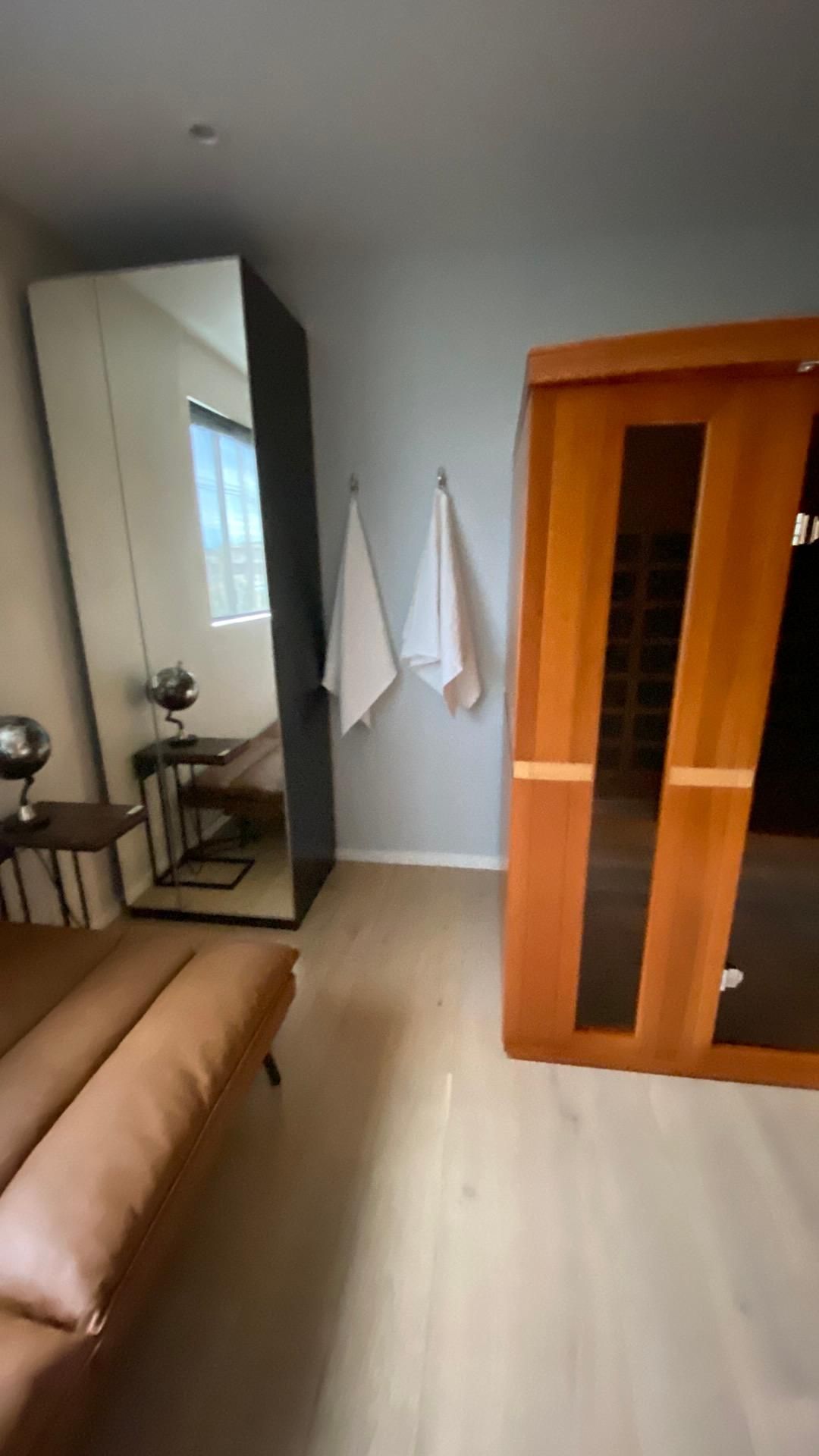 A room with a couch , a mirror , and a sauna.