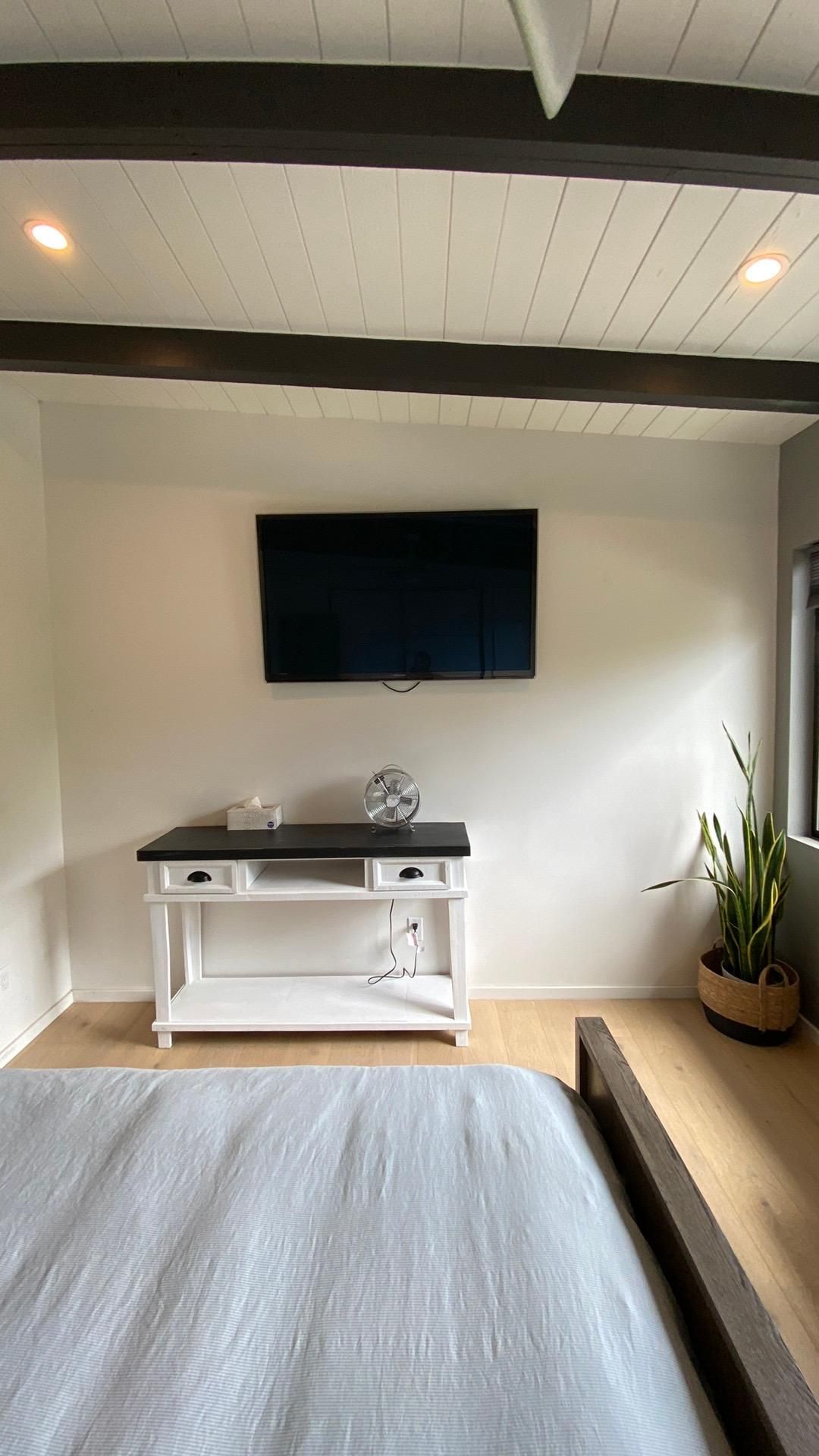 A bedroom with a bed and a television on the wall.