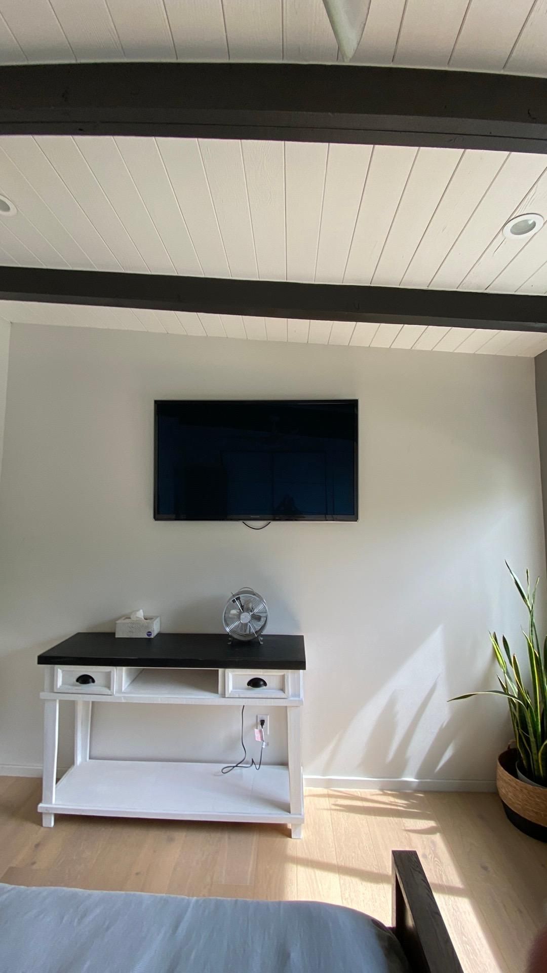 A living room with a flat screen tv mounted on the wall above a table.