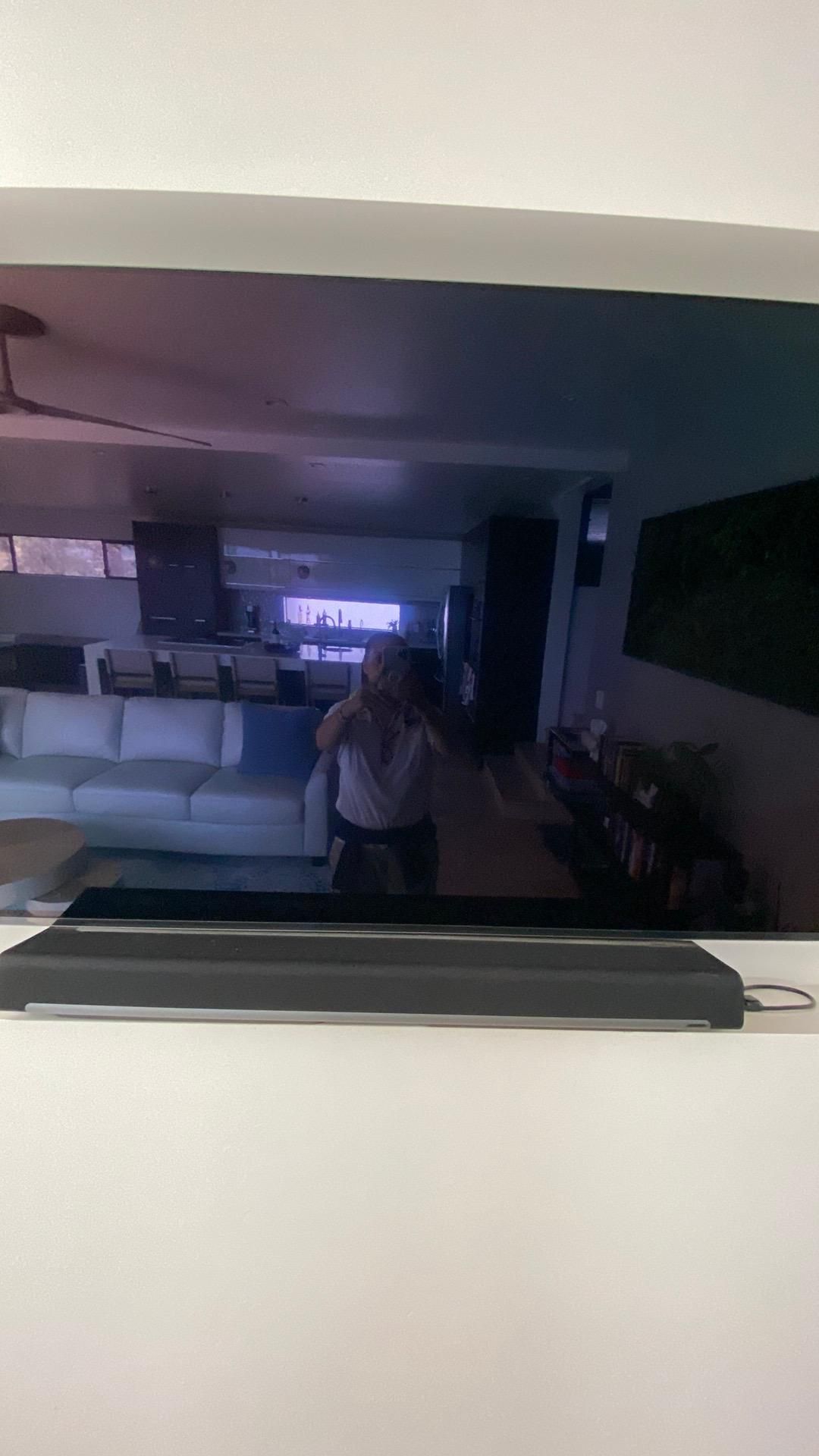 A person is taking a picture of a living room with a flat screen tv.