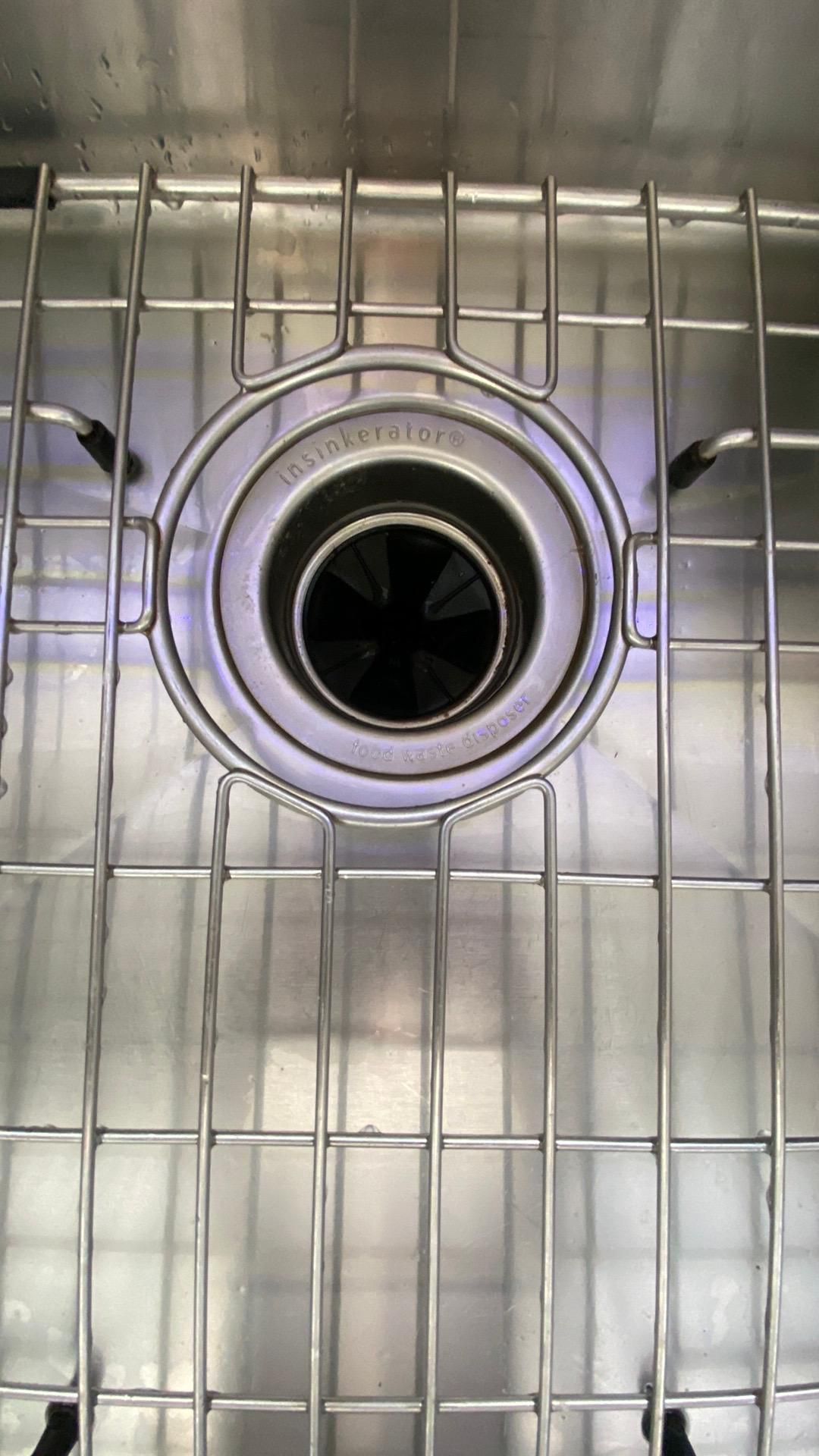 A close up of a stainless steel sink with a drain.