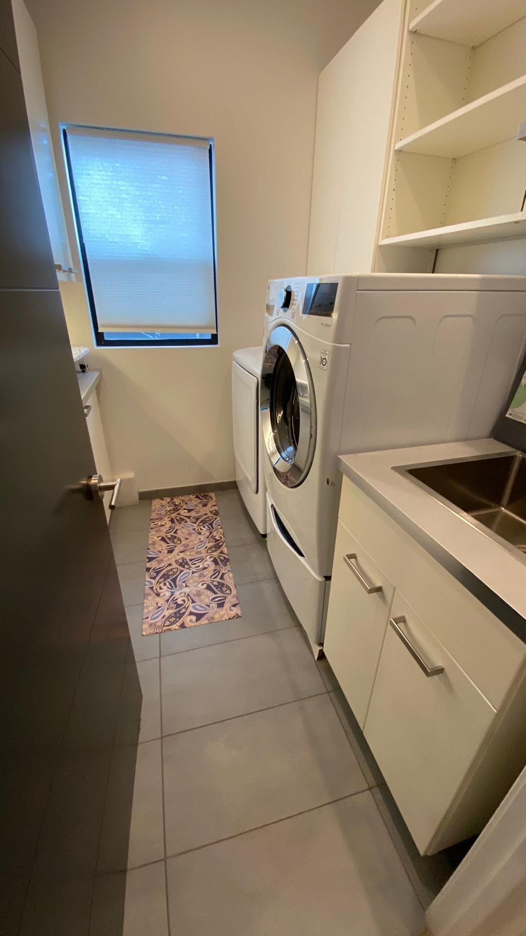 A laundry room with a washer and dryer and a sink.