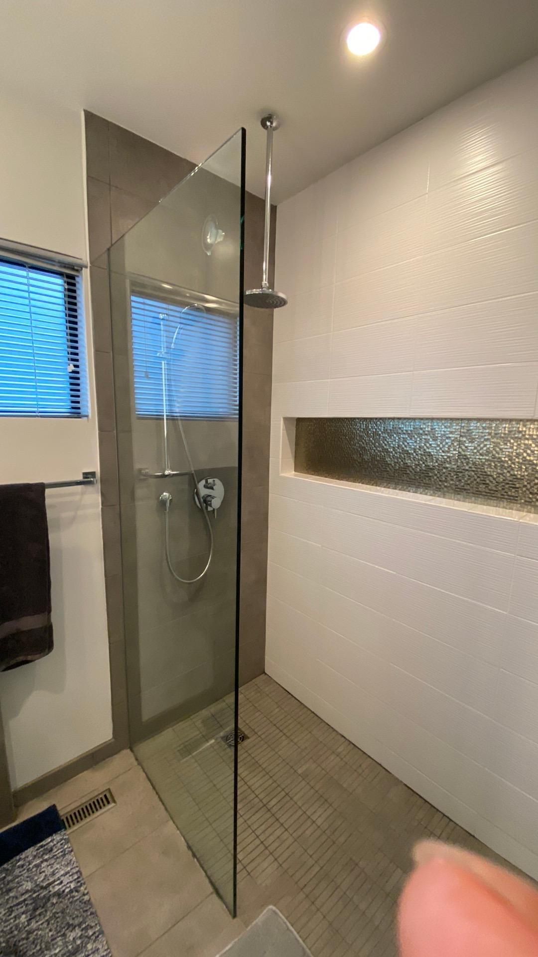A bathroom with a walk in shower and a window.