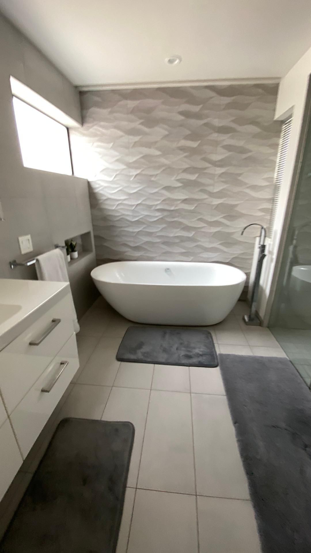 A bathroom with a bathtub , sink , and shower.
