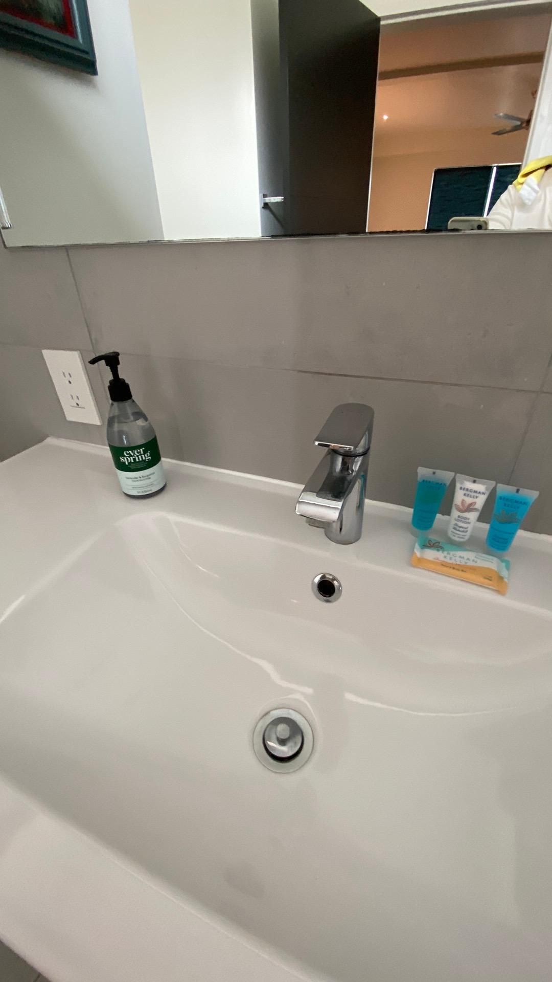 A bathroom sink with a soap dispenser and a mirror.