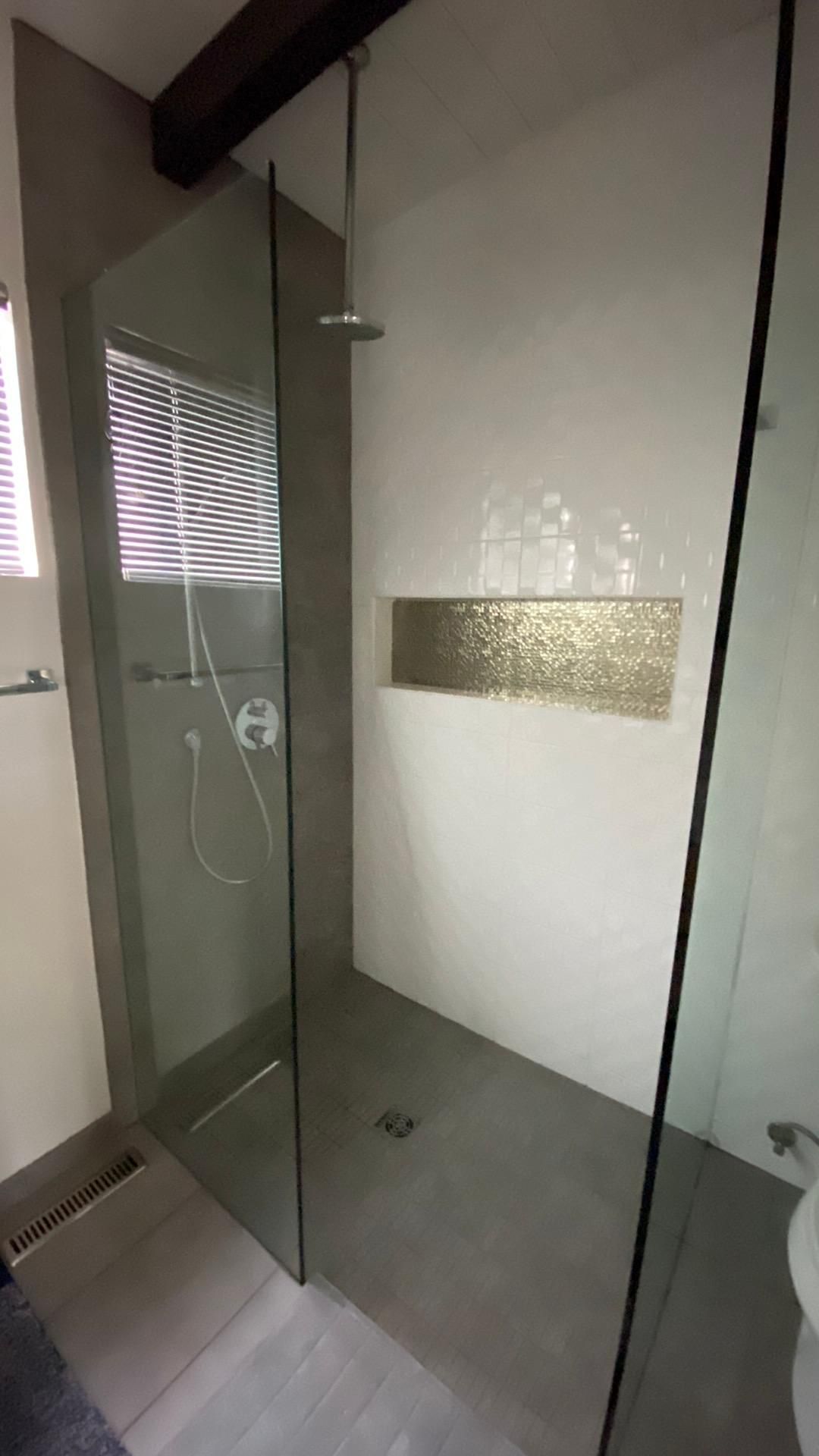 A bathroom with a walk in shower and a window.