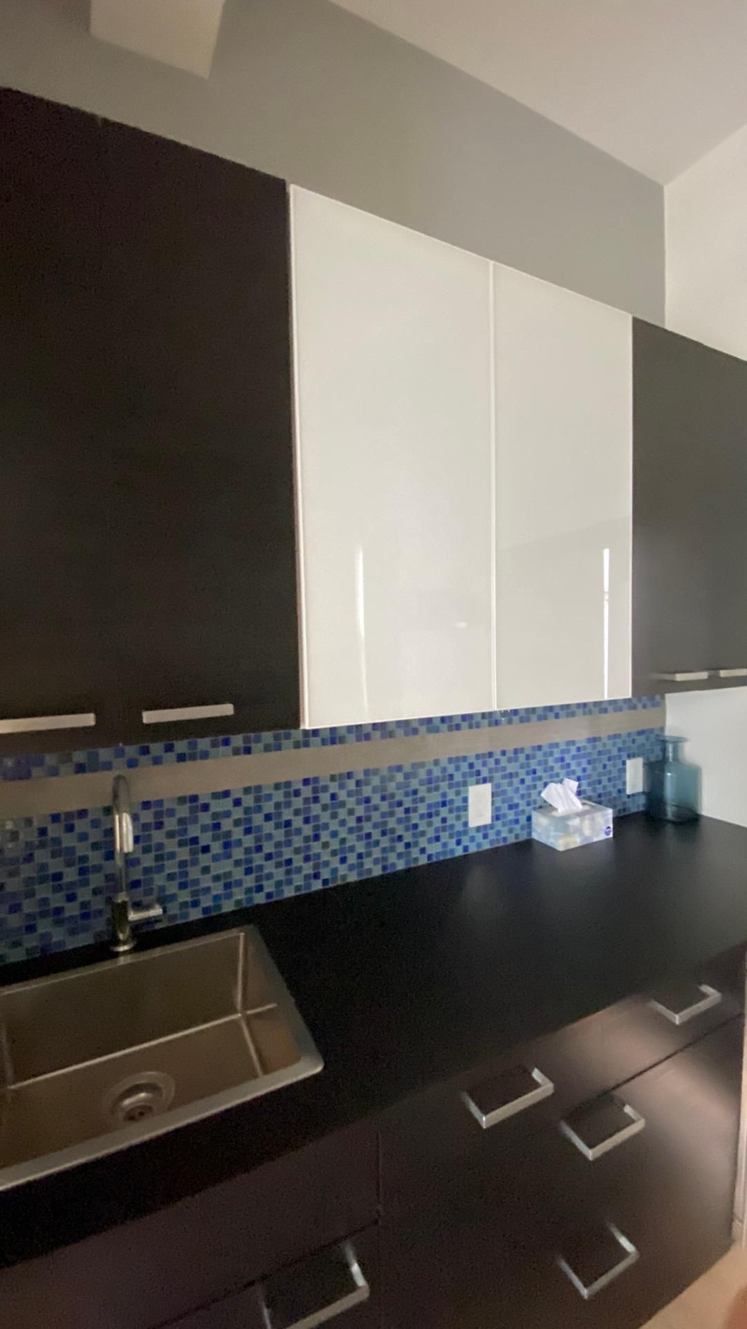 A kitchen with black cabinets and a stainless steel sink