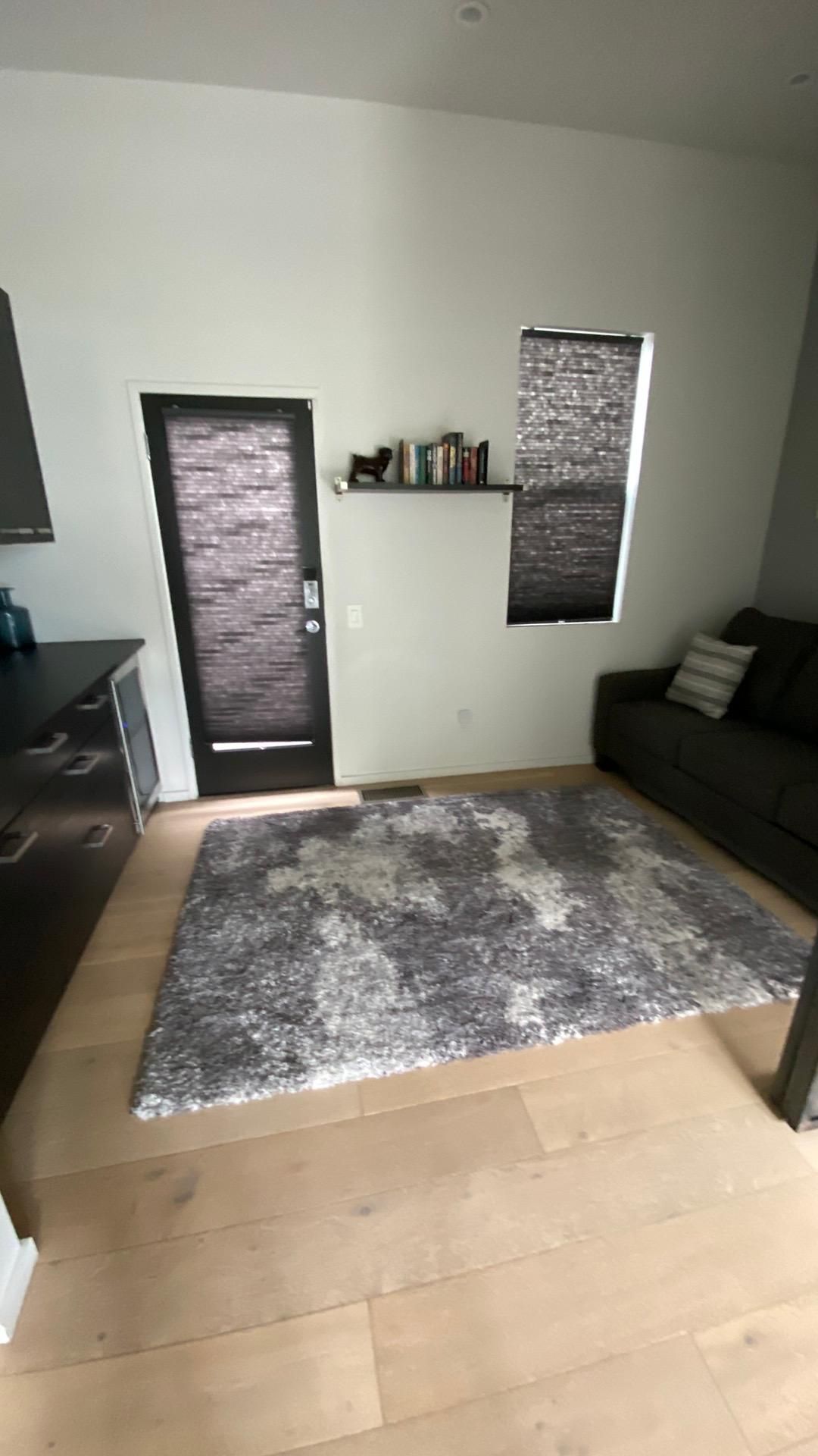 A living room with a couch , rug , and door.