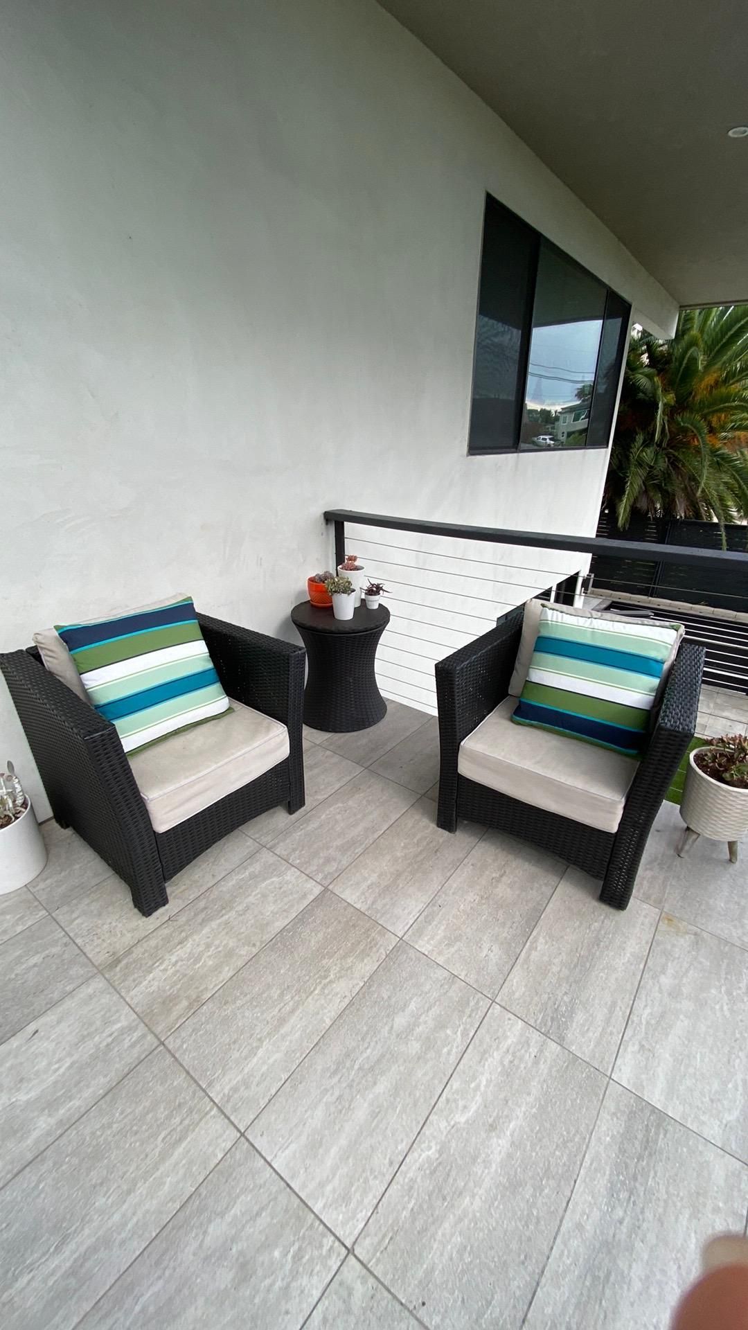 There are two chairs and a table on the balcony.